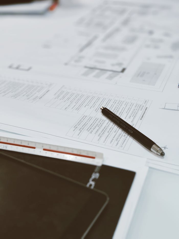 Top view of architectural blueprints, pen, and scale ruler on a designer